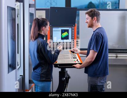 Factory workers talking to each other near CNC machine in industry Stock Photo