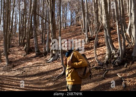 Smiling man with backpack standing in forest Stock Photo