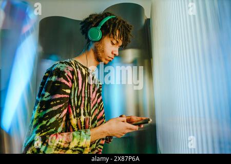 Man in casuals using smart phone and listening to music Stock Photo