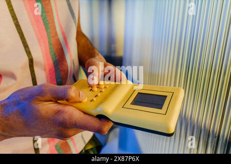 Man playing yellow colored handheld game near striped wall Stock Photo