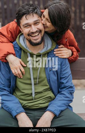 Smiling woman kissing man wearing jacket Stock Photo