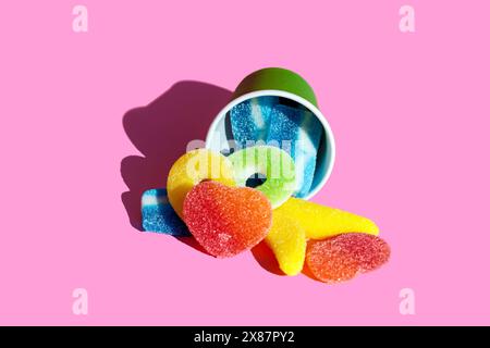 Jelly candies lying with cup over pink background Stock Photo
