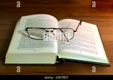 Forgotten glasses lie on an open book lying on the table. High quality photo Stock Photo