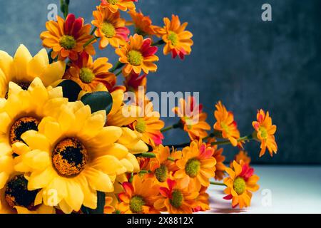 Bouquet yellow, orange flowers against dark concrete wall Stock Photo