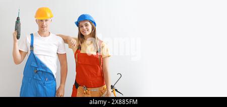 Happy young couple with construction tools on light background with space for text Stock Photo