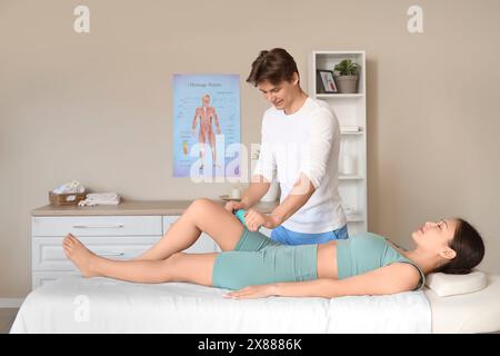 Male therapist massaging young woman's leg with roller in spa salon Stock Photo