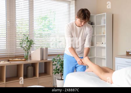 Male therapist massaging young woman's foot in spa salon Stock Photo