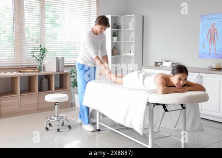 Male therapist massaging young woman's leg in spa salon Stock Photo