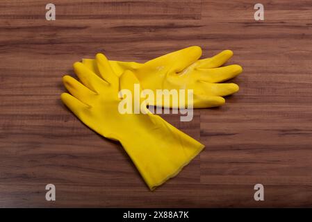 Pair of yellow rubber washing cleaning gloves isolated on wooden background. Stock Photo