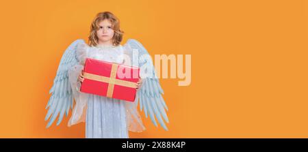 Angel child hold gift present. Angel child. Isolated studio shot. Cute kid with angel wings. Banner for website header design. Stock Photo