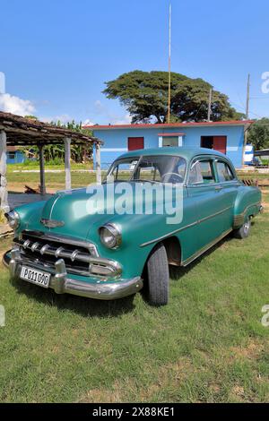 305 Front-side view, old green American classic car -Chevrolet 1952- stopped next to the train station building, Manaca Iznaga Estate. Trinidad-Cuba. Stock Photo