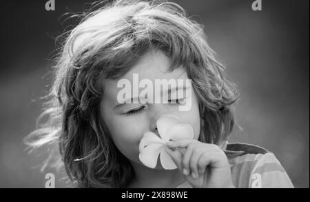 Close up face of cute child outdoors. Funny child smelling plumeria flower. Dreamy kids face. Daydreamer child portrait close up. Dreams and Stock Photo