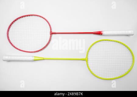 Overhead view of two colorful badminton rackets with red and yellow frames and white grips, isolated on a clean white background, with space for text Stock Photo