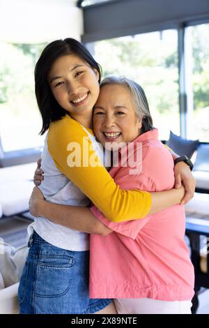 At home, Asian middle-aged mother and young adult daughter hugging Stock Photo