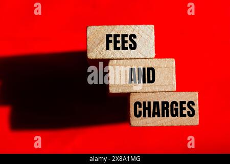 Fees and charges words written on wooden blocks with red background. Conceptual fees and charges symbol. Stock Photo