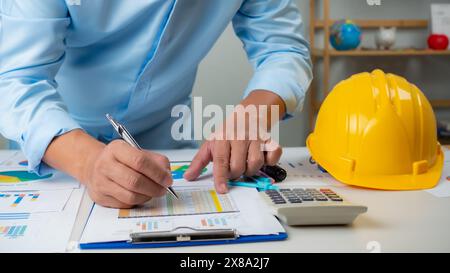 Architect or engineer sitting at desk in office, Cost calculation, Construction planning, structural calculation, Project construction cost planning a Stock Photo