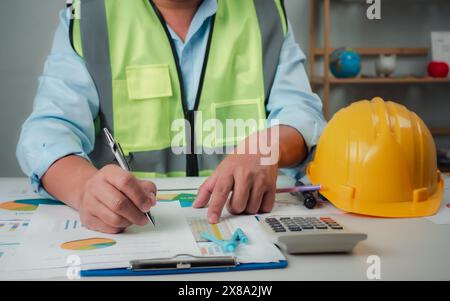 A foreman sits at a desk in an office, Calculating costs, Planning construction, Calculating structures, Planning and calculating project construction Stock Photo