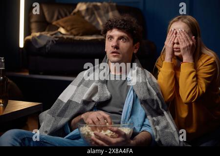 Young couple watching scary movie together Stock Photo