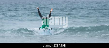 A panoramic image of an enthusiastic surfer attempting a headstand on his surfboard in the Sand Bandit Showdown surfing competition at Gt Western Grea Stock Photo