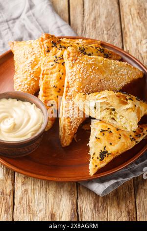 Chicken Puff Pastry appetizers filled with a homemade creamy chicken filling served with sauce closeup on the plate on the wooden table. Vertical Stock Photo