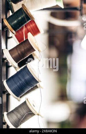 Spools of colorful thread on a rack in a sewing workshop Stock Photo