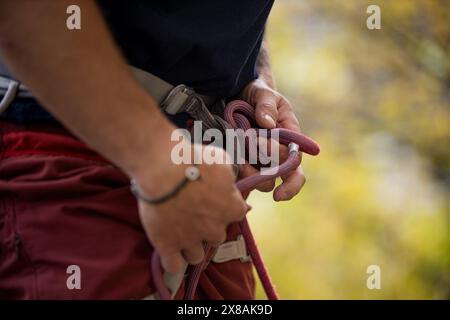 Man tying climbing knot with autumn tree background Stock Photo