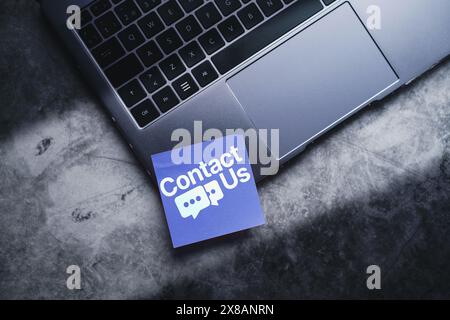 Adhesive note on laptop with Contact Us concept. Customer support hotline people connect. Stock Photo