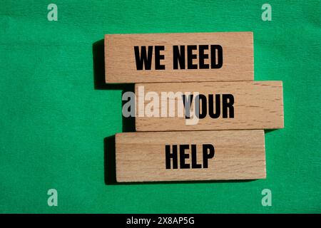 We need your help words written on wooden blocks with green background. Conceptual we need your help symbol. Copy space. Stock Photo