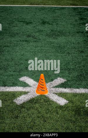 An orange athletic cone on a turf football field. Stock Photo