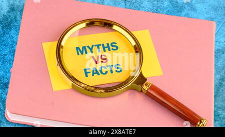 Business, financial and fact vs myth concept. Copy space. Concept words, symbol Fact vs myth on a yellow business card with a magnifying glass on top Stock Photo