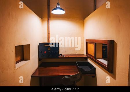 A small room with a desk, a chair, and an old radio transceiver. A window looks out to another part of the facility at the Lascaris War Rooms, Malta Stock Photo