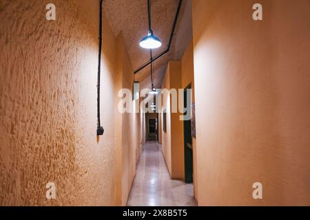 A long, narrow hallway with exposed wiring and overhead lights, in the Lascaris War Rooms, Valletta, Malta Stock Photo