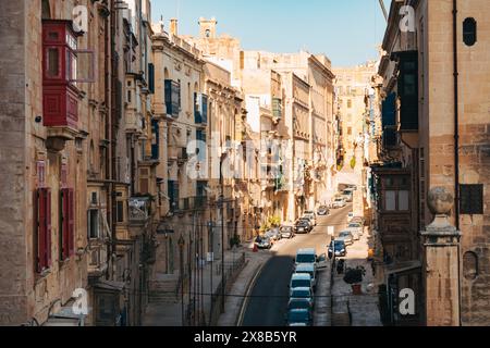 a street curves through the city of Sliema, Malta, lined with limestone apartment buildings in a traditional Maltese style Stock Photo