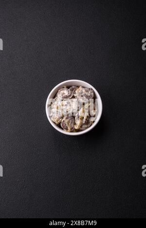 Boiled chicken hearts cut into slices with onions and cream sauce with salt and spices on a dark concrete background Stock Photo