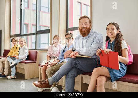 A group of people, including children and adults, sit patiently in a colorful waiting room. Stock Photo