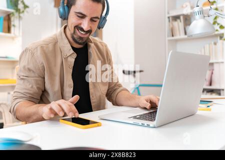 Smiling business man working on laptop at home office. Young student using computer remote studying Stock Photo