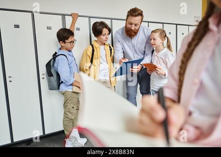 A man teacher is instructing a group of kids standing near lockers in a brightly lit classroom. Stock Photo