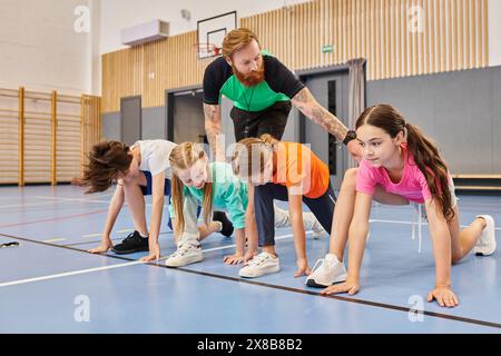 A diverse group of kids are engaging in a synchronized session of push ups on a gym floor, guided by their instructor. Stock Photo