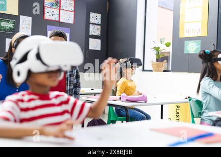 In school, diverse group of students wearing virtual reality headsets in the classroom, copy space Stock Photo