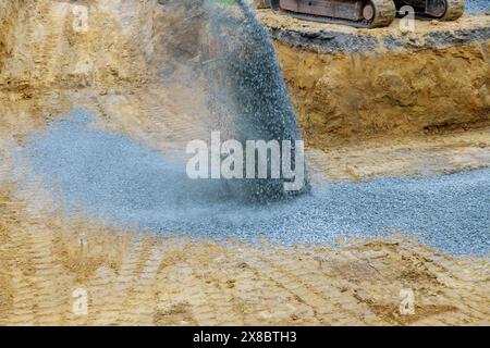 An excavator fills irregularities in excavations with granite rubble base so that concrete foundation can be laid Stock Photo