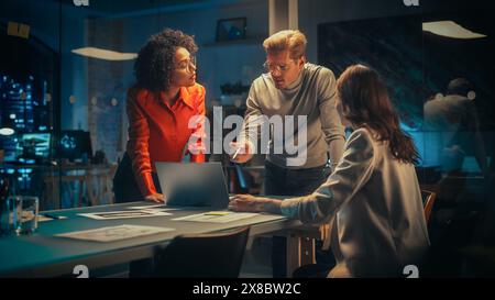 Positive Group of Managers Having a Team Meeting Long After Work Hours in the Night. Inspired Colleagues Discussing Annual Financial and Marketing Reports. Teamwork in Creative Office. Stock Photo