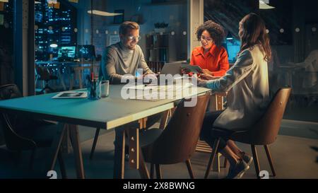 Positive Group of Managers Having a Team Meeting Long After Work Hours in the Night. Inspired Colleagues Discussing Annual Financial and Marketing Reports. Teamwork in Creative Office. Stock Photo