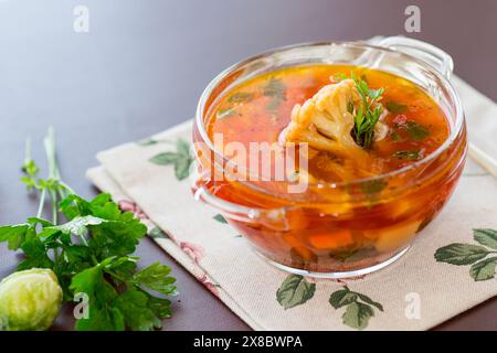 vegetable soup with Brussels sprouts and cauliflower, in a glass plate on a wooden table Stock Photo