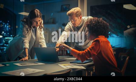 Positive Group of Managers Having a Team Meeting Long After Work Hours in the Night. Inspired Colleagues Discussing Annual Financial and Marketing Reports. Teamwork in Creative Office. Stock Photo