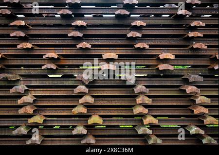 rusted pieces of railway and metal sleepers stacked together outside Stock Photo