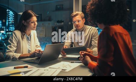 Group of Young Successful Businesspeople Making a Team Meeting in Conference Room in Creative Agency. Excited Diverse Team Using Laptop Computer, Discussing a New Corporate Strategy. Stock Photo