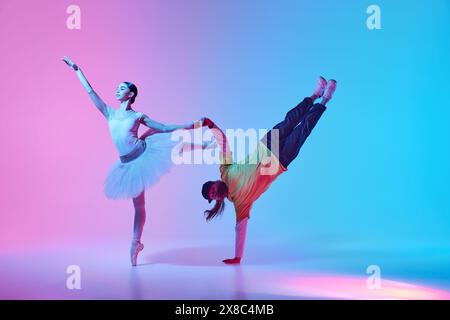 Classic and sport fusion. Beautiful young girl, ballet dancer making creative dance collaboration with breakdancer on gradient background in neon Stock Photo