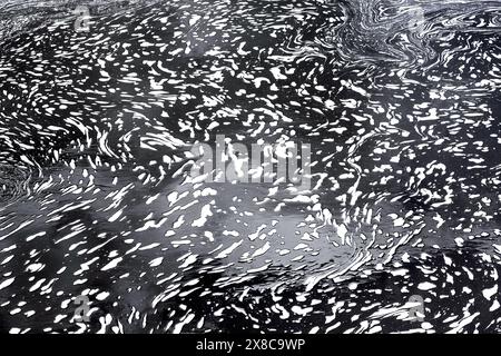 Foam and reflected light creating abstract designs on surface of flowing river - Preuilly-sur-Claise, Indre-et-Loire (37), France. Stock Photo