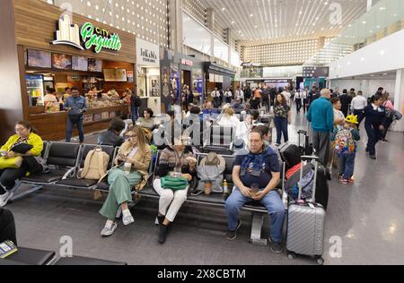 Airport passengers sitting waiting for their flight inside the Terminal; Mexico City International Airport, Mexico City Mexico. Mexico Travel Stock Photo