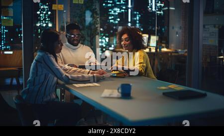 Excited Diverse Team Celebrating a Corporate Win, High Five Each Other Around the Table. Group of Young Successful Businesspeople Making a Corporate Meeting in Conference Room in Creative Agency. Stock Photo